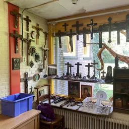 Uitgestalde religieuze artikelen: kruis-wanddecoraties, beeldjes en andere devotionalia in een kringloopwinkel