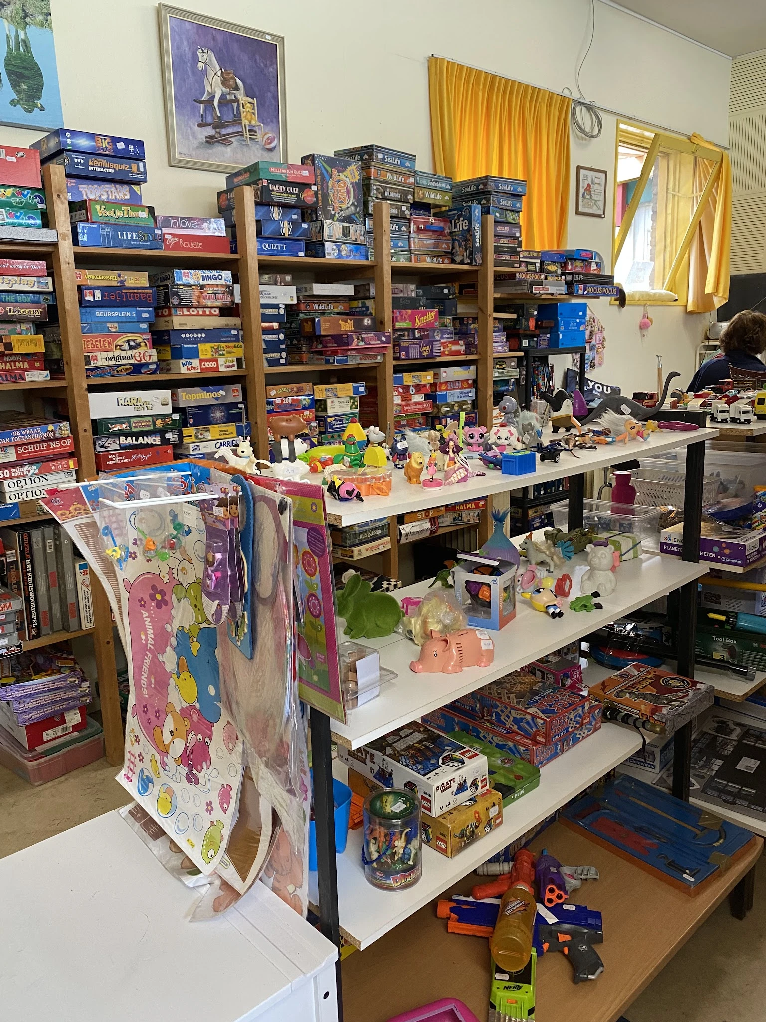Tafels vol speelgoed, poppen, actiefiguren en kinderartikelen in een kringloopwinkel