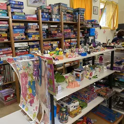 Tafels vol speelgoed, poppen, actiefiguren en kinderartikelen in een kringloopwinkel