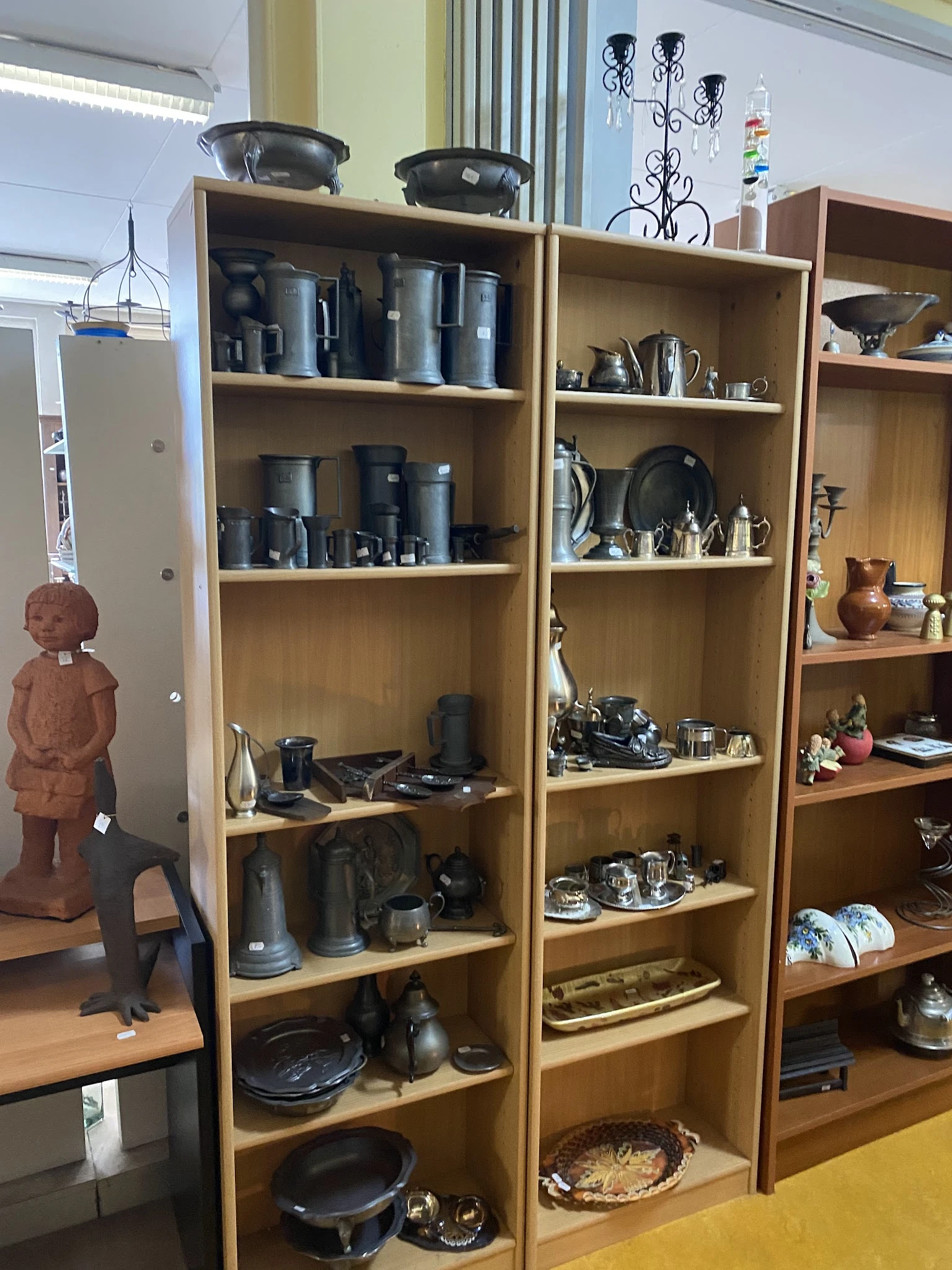 Houten stellingen met huishoudelijke items zoals pannen, servies, glazen en decoratieve objecten