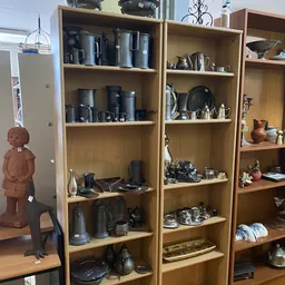 Houten stellingen met huishoudelijke items zoals pannen, servies, glazen en decoratieve objecten