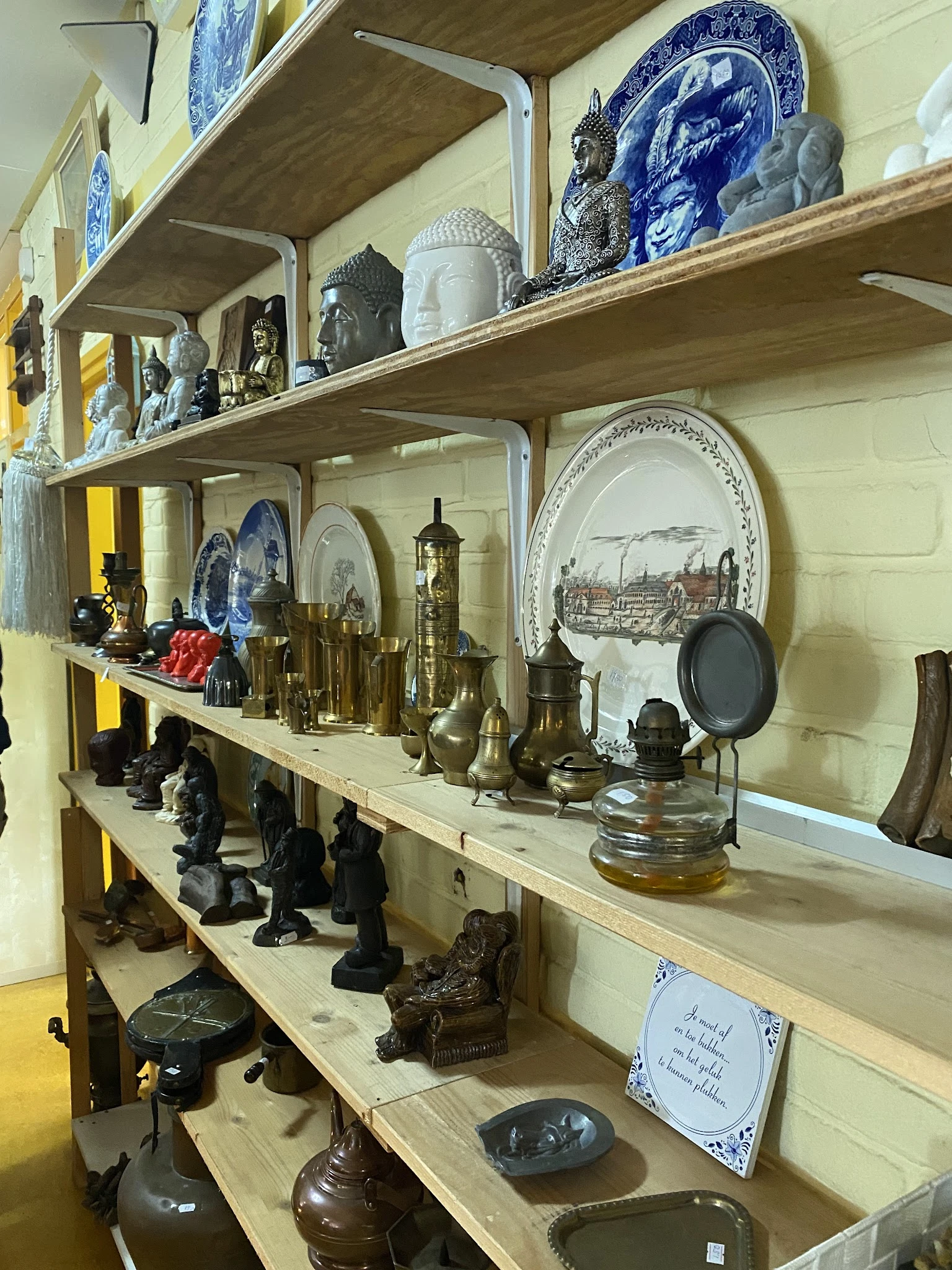 Stellingen met verzameling van koperen huishoudartikelen, borden, beeldjes en decoratieve voorwerpen