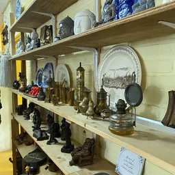 Stellingen met verzameling van koperen huishoudartikelen, borden, beeldjes en decoratieve voorwerpen