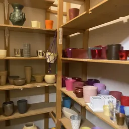 Houten stellingen met diverse kaarsen in verschillende kleuren en maten uitgestald