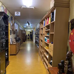 Winkelgang met houten kasten en stellingen vol boeken en spullen aan beide zijden