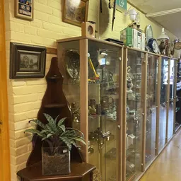 Kringloopwinkelinterieur met glazen vitrinekastjes vol verzamelobjecten en decorstukken