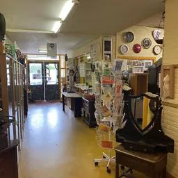 Winkelinterieur met stellingen, toonbank, klokken aan de muur en diverse spullen uitgestald