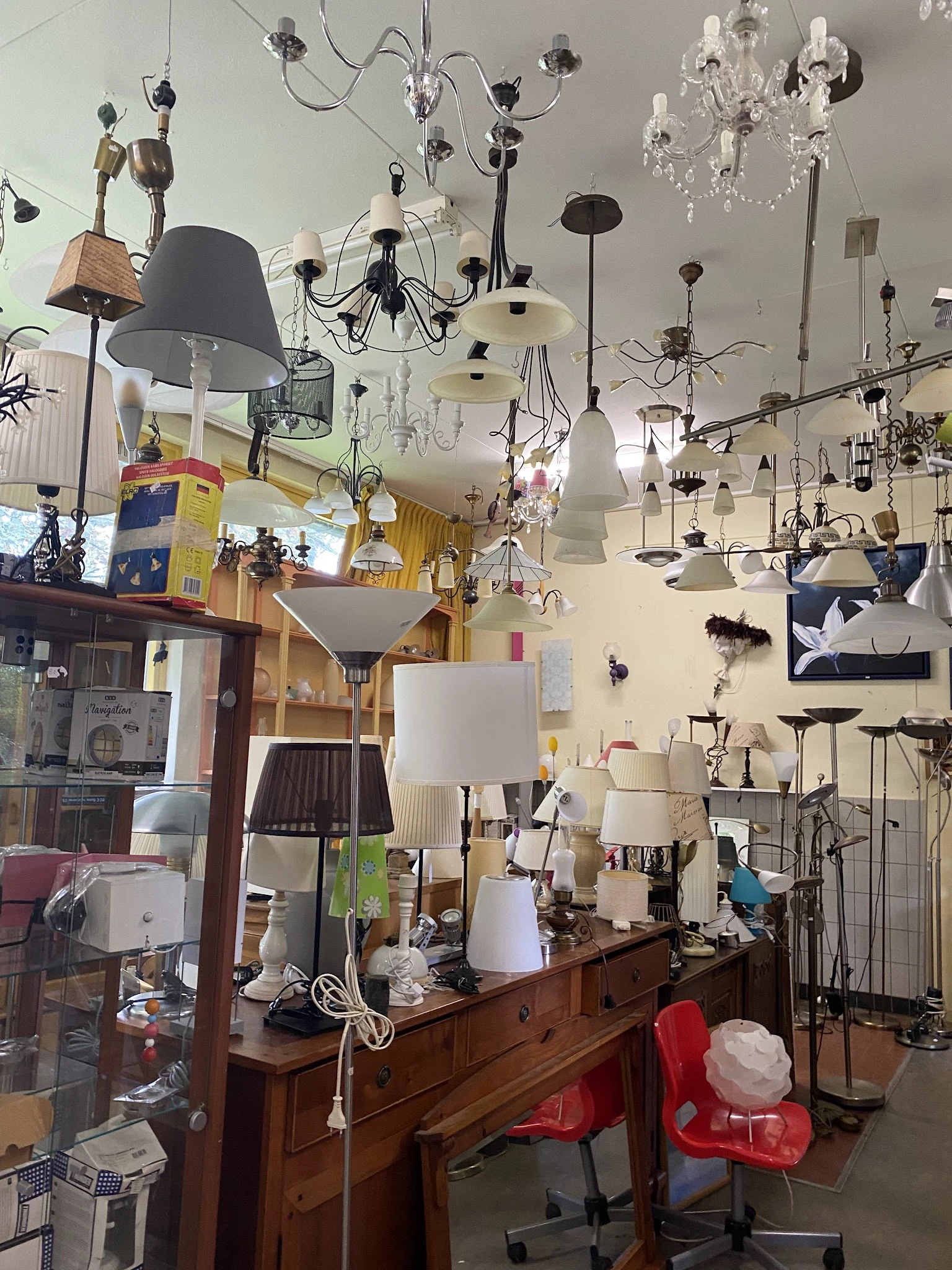 Hangende lampen en verlichtingsarmaturen in diverse stijlen en kleuren, dicht tegen elkaar opgehangen aan het plafond