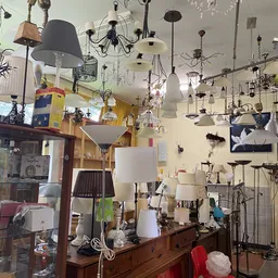 Hangende lampen en verlichtingsarmaturen in diverse stijlen en kleuren, dicht tegen elkaar opgehangen aan het plafond