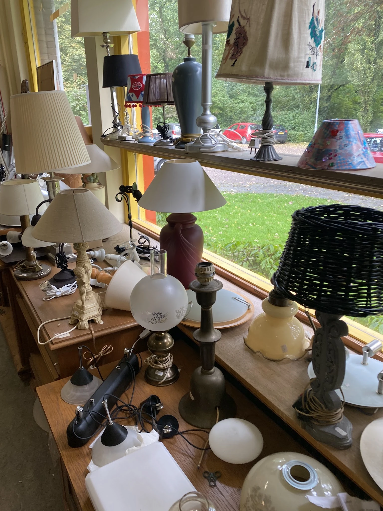 Diverse tafellampjes en decoratieve items uitgestald op een tafel bij een raam
