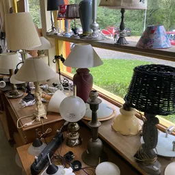 Diverse tafellampjes en decoratieve items uitgestald op een tafel bij een raam