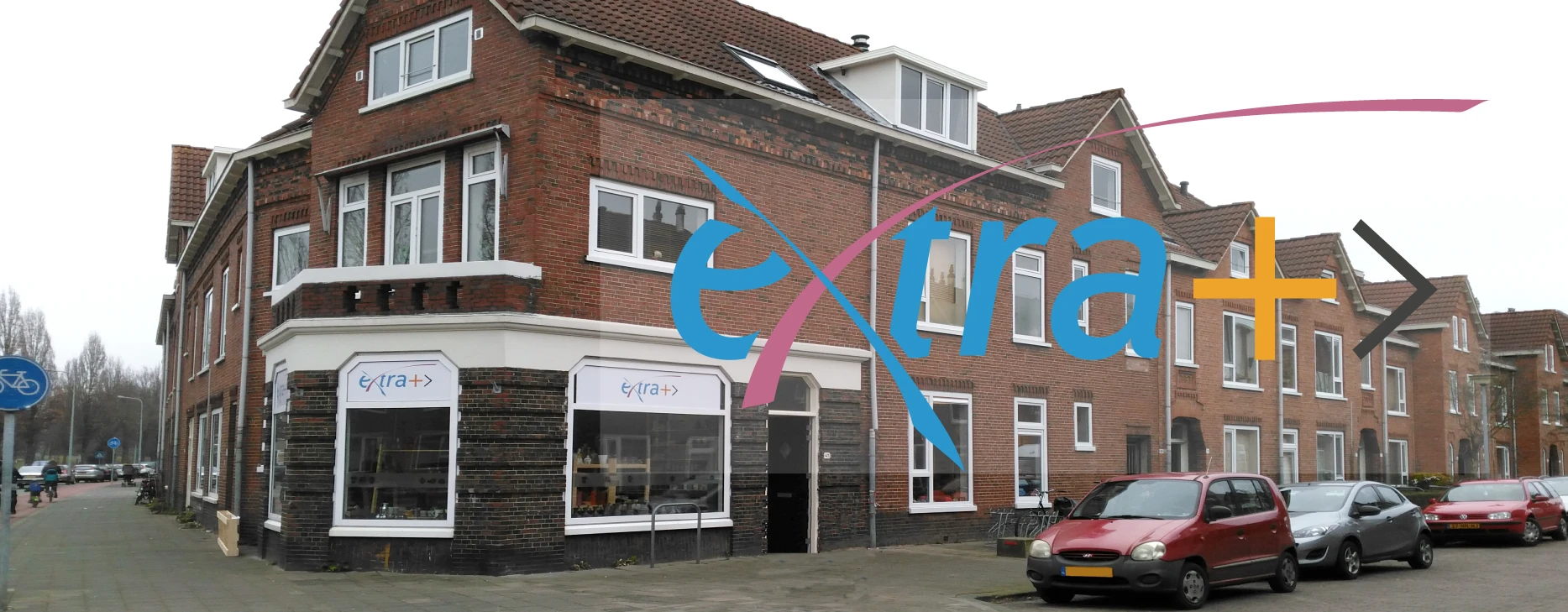 Voorgevel van bakstenen winkelpand met grote blauwe logo-stickers
