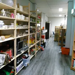 Winkelvloer met stellingen vol huishoudartikelen, boeken en diverse spullen in een kringloopwinkel