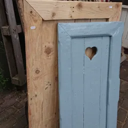 Twee houten vogelhuisjes, één onafgewerkt en één geschilderd in lichtblauw met hartuitsnijding
