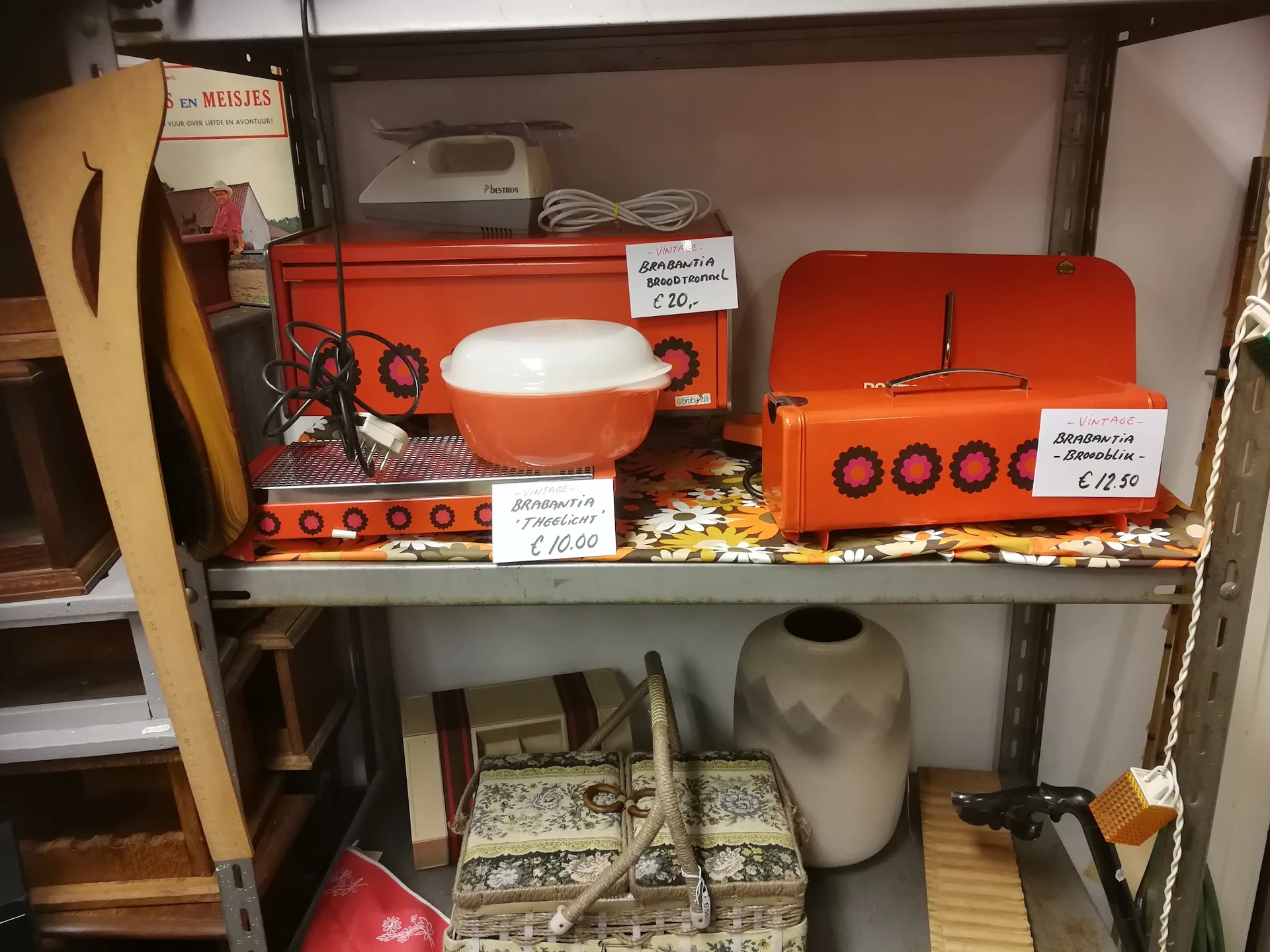 Stellingkast met oranje retro keukenapparatuur en huishoudelijke artikelen met prijskaartjes