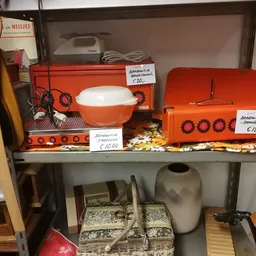 Stellingkast met oranje retro keukenapparatuur en huishoudelijke artikelen met prijskaartjes