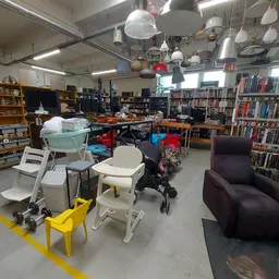 Winkelvloer met boekenkasten, zithoeken, lampen en diverse meubels in een kringloopwinkel
