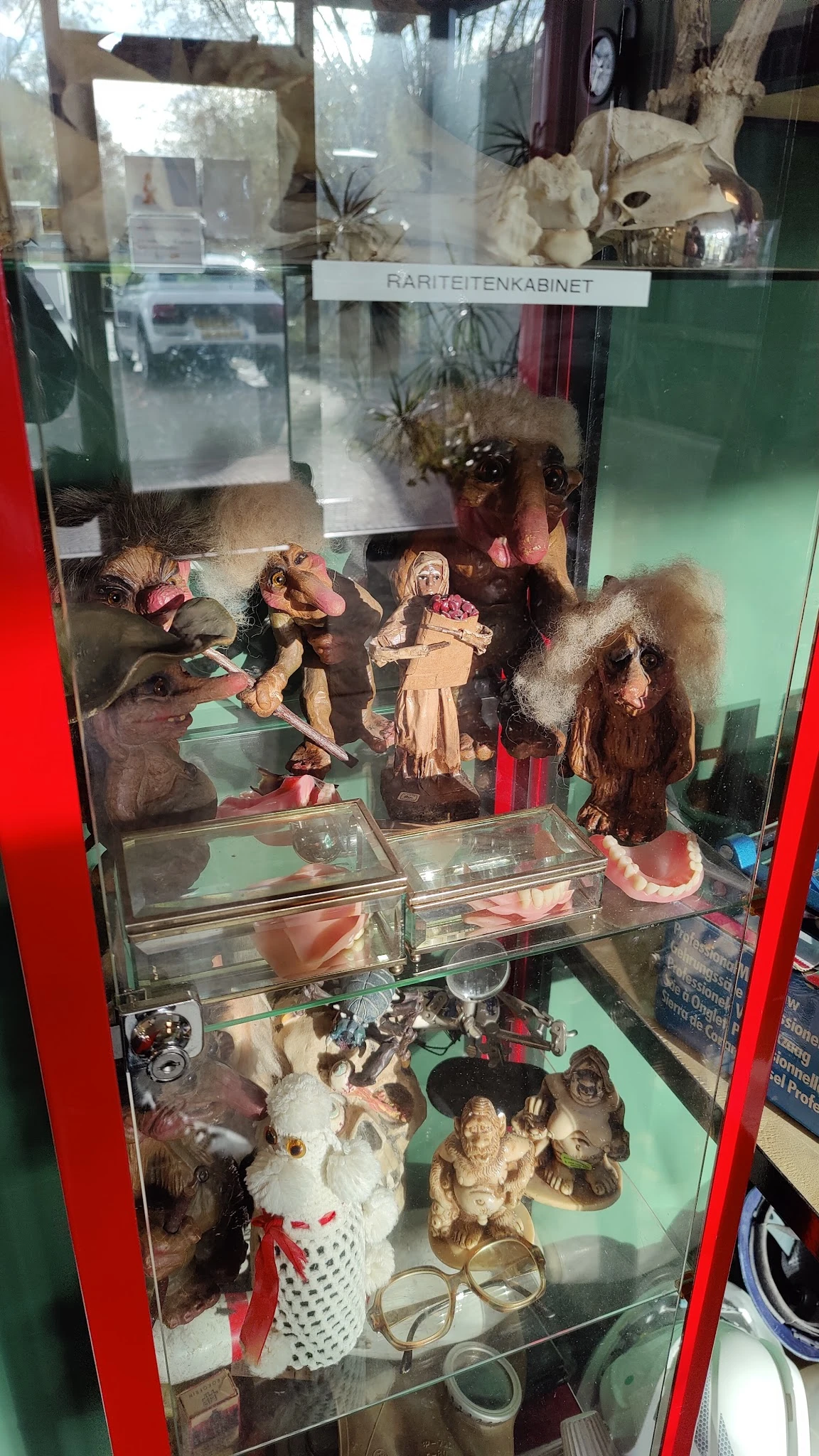 Glazen vitrinekast met verzameling vintage poppen en speelgoedbeelden