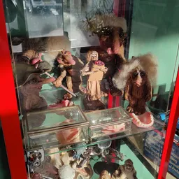 Glazen vitrinekast met verzameling vintage poppen en speelgoedbeelden
