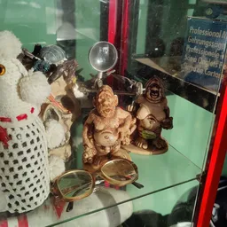 Vitrine met diverse tweedehands items: decoratieve houten beeldjes, schedel, bril en andere curiosa