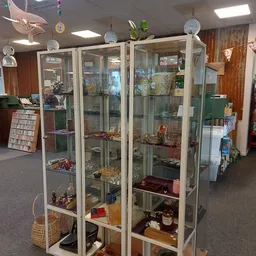 Glazen vitrinekasten met diverse tweedehands artikelen, waaronder porselein, decoratieve voorwerpen en andere huishoudelijke 