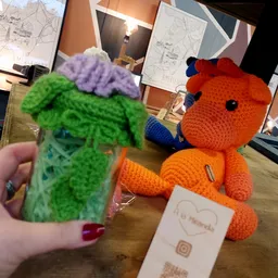 Close-up van twee gebreide knuffels: een groen monster met paars haar en een oranje dier met blauwe accenten