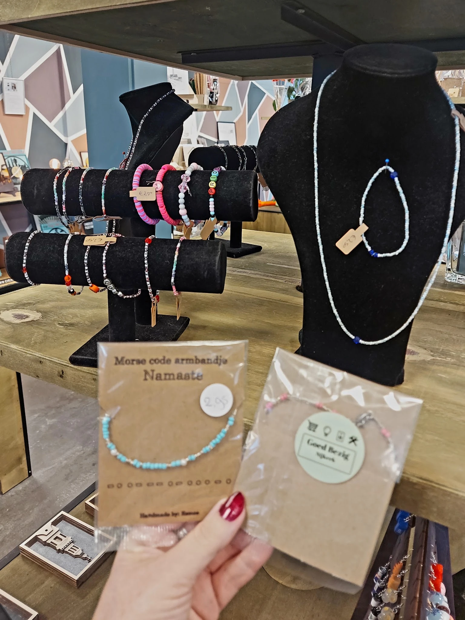 Uitgestalde armbanden op zwarte busten, waaronder morse code armbandjes met het label 'Namaate'