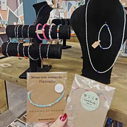 Uitgestalde armbanden op zwarte busten, waaronder morse code armbandjes met het label 'Namaate'