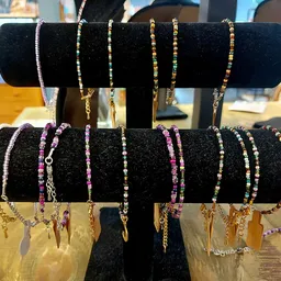 Uitgestalde armbanden met kralen en metalen details op zwarte displaystandaards