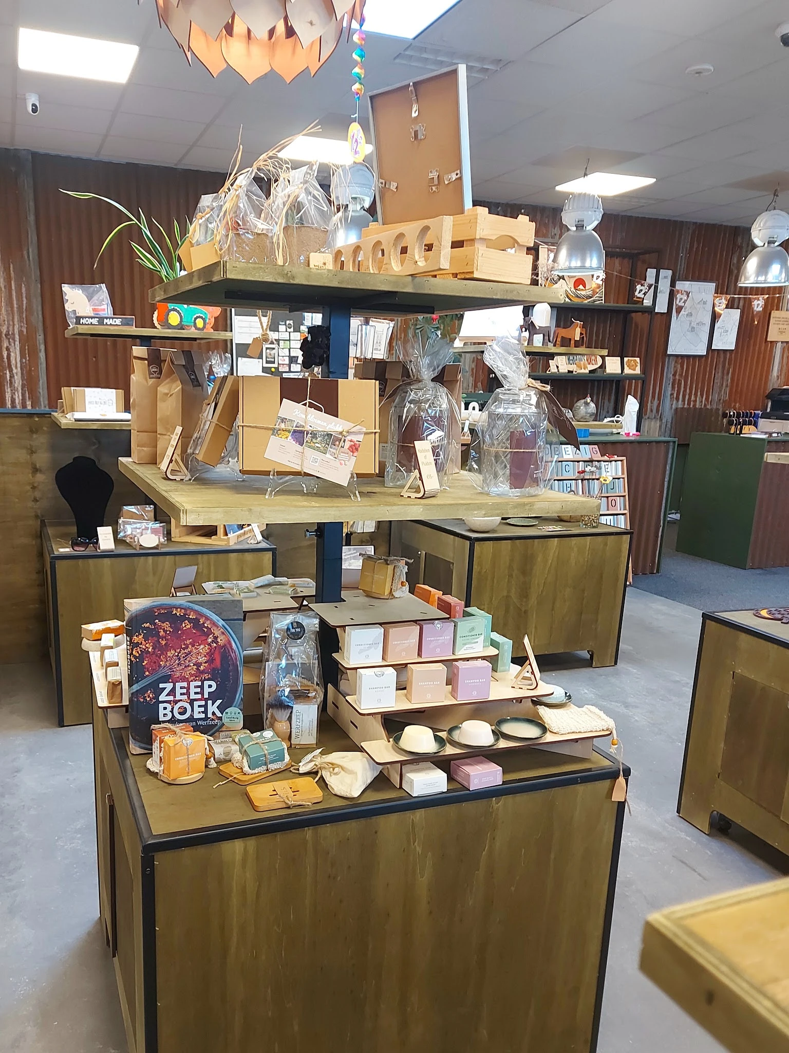 Uitgestalde tweedehands spullen op houten vitrines, waaronder boeken, kaarsen, servies en decoratieve artikelen