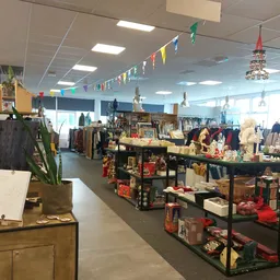 Winkelvloer met diverse meubels, decoratie en huishoudartikelen op tafels en stellingen, versierd met slingers