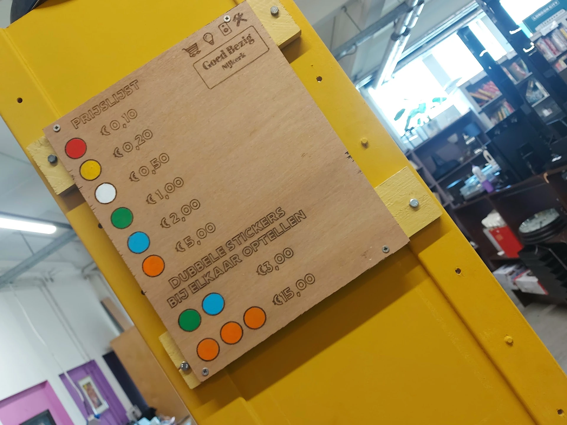 Geel bord met prijskaartjes en gekleurde stippen als categorie-aanduidingen