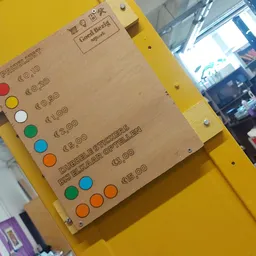 Geel bord met prijskaartjes en gekleurde stippen als categorie-aanduidingen