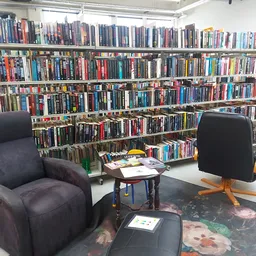 Zithoeken met twee fauteuils voor een grote boekenstelling vol dvd's en films in de kringloopwinkel