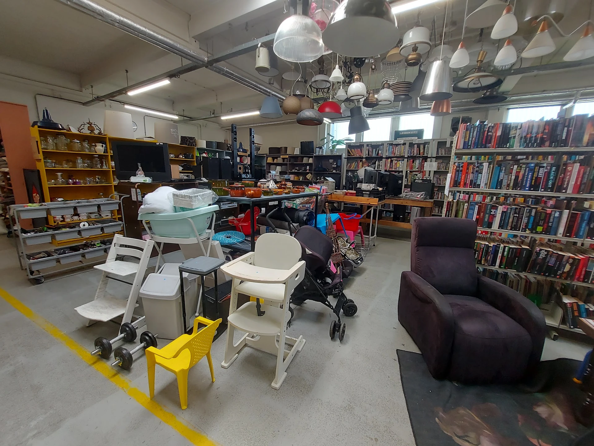 Winkelvloer met boekenrekken, meubels, lampen en diverses spullen in een kringloopwinkel