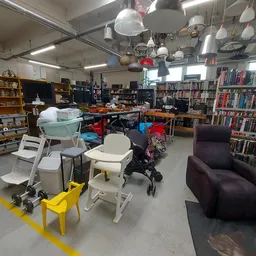 Winkelvloer met boekenrekken, meubels, lampen en diverses spullen in een kringloopwinkel