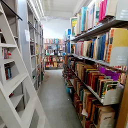 Gangpad tussen boekenrekken en kasten in kringloopwinkel met diverse boeken en spullen