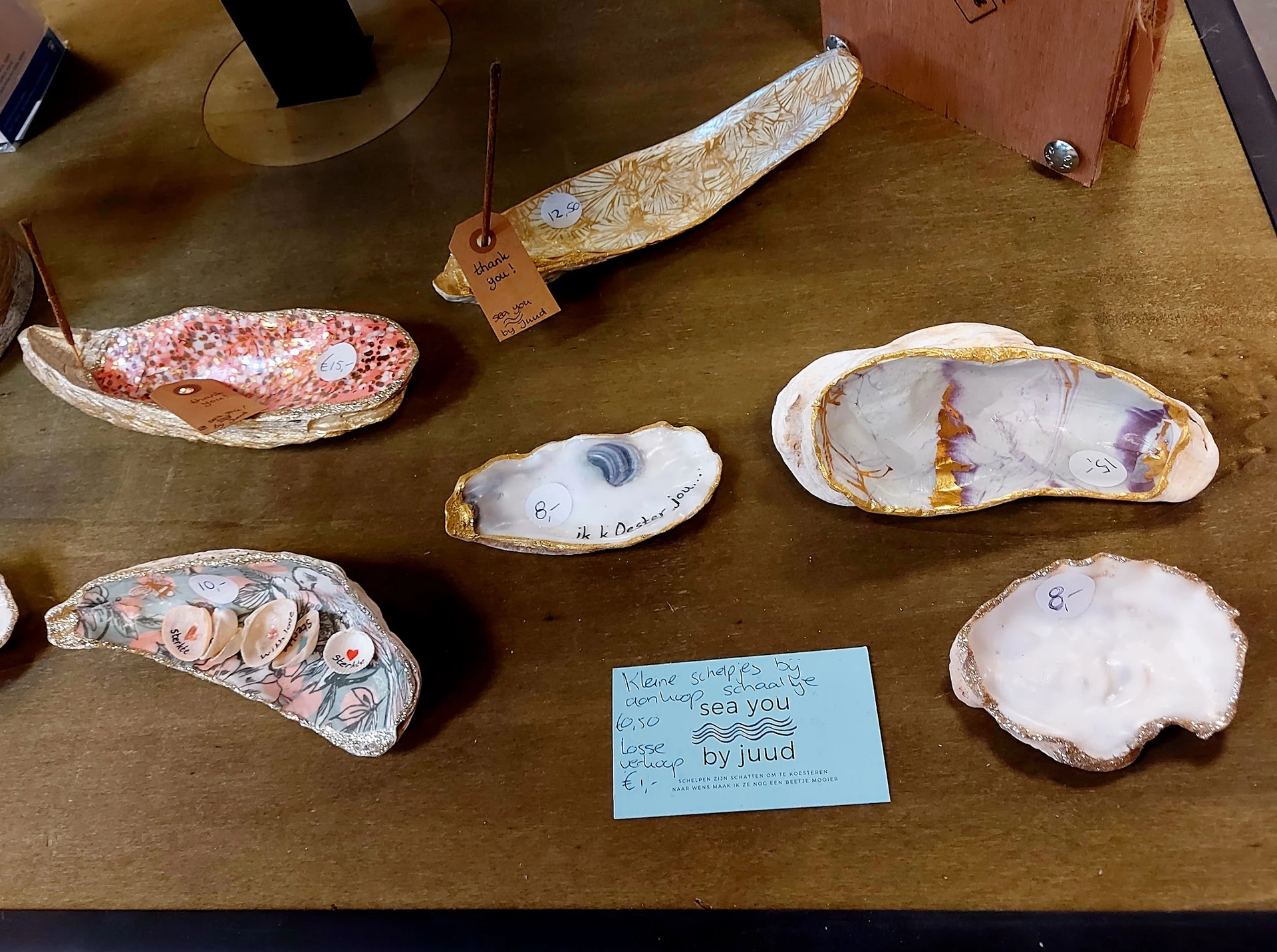 Uitgestalde handgemaakte items met decoratieve schilderingen op houten schelpvormen op een tafel
