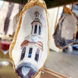 Close-up van een wit porselein schoentje met goudkleurige rand, beschilderd met een kerkgebouw met koepel en ramen