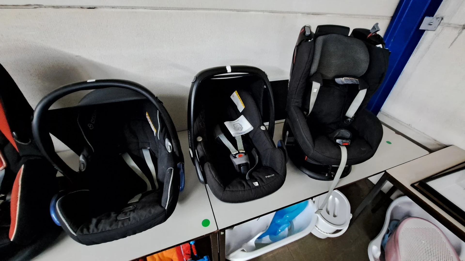 Drie autostoelen voor baby's en peuters in zwart, uitgestald op een tafel