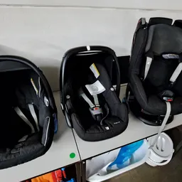 Drie autostoelen voor baby's en peuters in zwart, uitgestald op een tafel