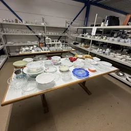 Tafel met uitgestald serviesgoed: borden, schalen, glazen en ander aardewerk in verschillende kleuren en stijlen