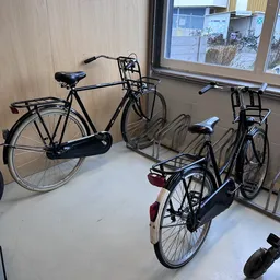 Drie tweedehands fietsen uitgestald in de winkel, waaronder een zwarte stadfiets en twee zwarte racefietsen