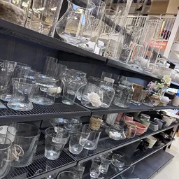 Glazen glazen en drinkglazen op zwarte stellingplanken in de winkel