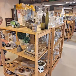 Houten display met huishoudelijke artikelen, decoraties en handwerk in een kringloopwinkel
