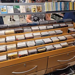 Houten kastje met meerdere laden vol cd's en dvd's uitgestald in kringloopwinkel