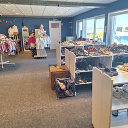 Winkelvloer met kledingrek, schoenen op planken en diverse tweedehands artikelen uitgestald