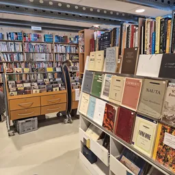 Winkelbinnenruimte met boekenrekken aan de linkerzijde en uitgestalde boeken op wandplanken aan de rechterzijde, met een hout