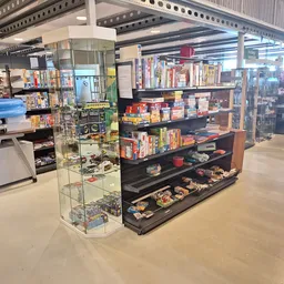 Overzicht van de winkelvloer met verschillende vitrinekasten en stellingen vol met tweedehands spullen en merchandise