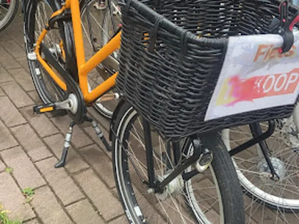 Tweedehands fietsen met mand, waaronder een oranje fiets en een fiets met winkeltas